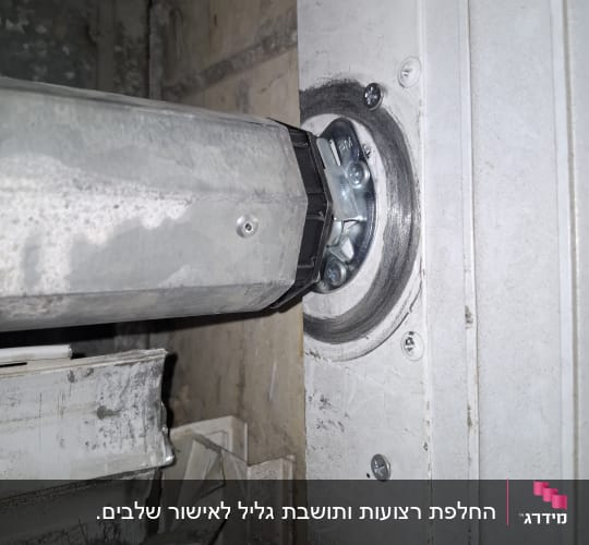 תקריב של מנגנון ציר ומנוע תריס גלילה חשמלי בתוך ארגז תריס